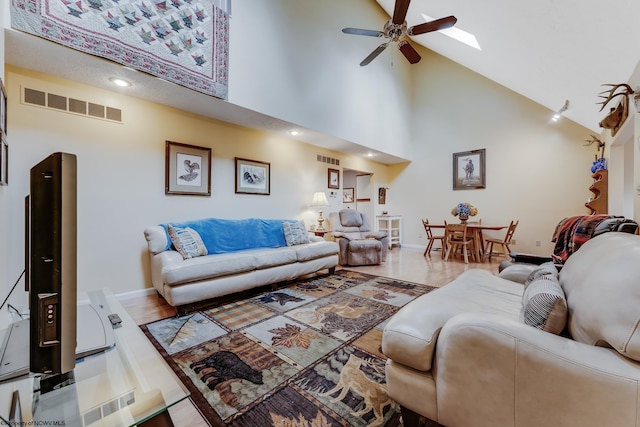 living room featuring a ceiling fan, high vaulted ceiling, visible vents, and baseboards