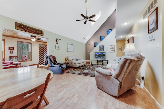 living room featuring visible vents, high vaulted ceiling, a ceiling fan, light wood finished floors, and a skylight
