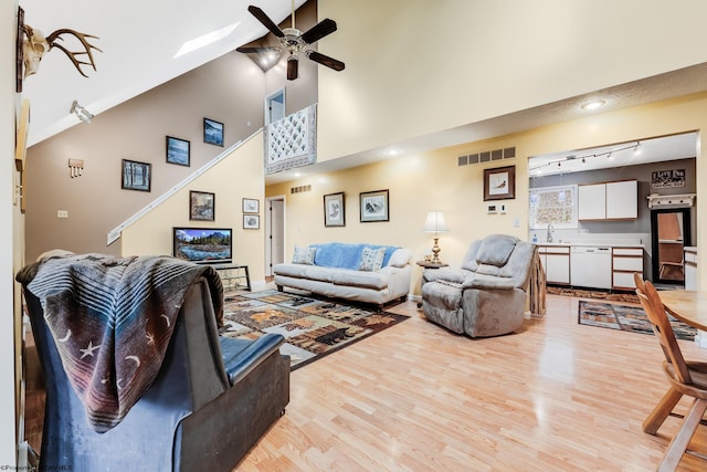 living room with ceiling fan, visible vents, light wood-type flooring, rail lighting, and high vaulted ceiling
