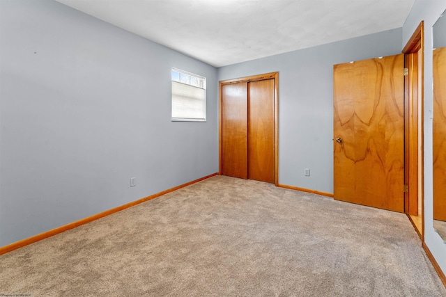 unfurnished bedroom featuring carpet flooring, baseboards, and a closet