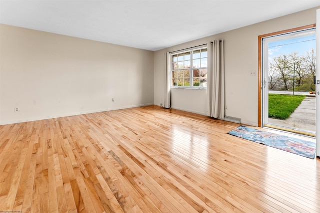 spare room with visible vents, light wood finished floors, and baseboards