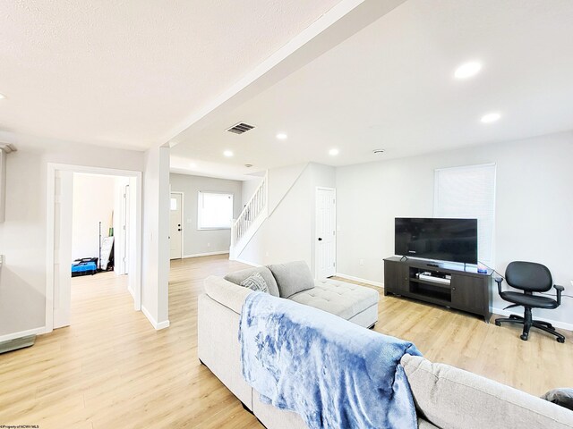 living area featuring stairs, baseboards, visible vents, and light wood-style floors