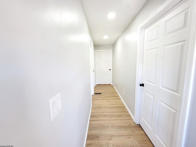 hall with baseboards, light wood-type flooring, recessed lighting, and visible vents