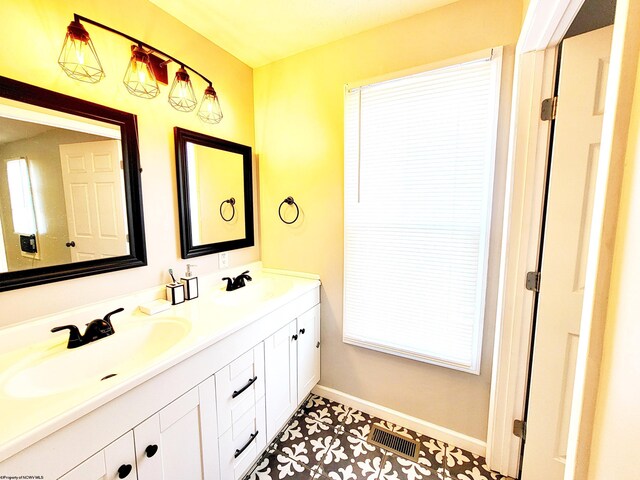 full bathroom with double vanity, baseboards, visible vents, and a sink
