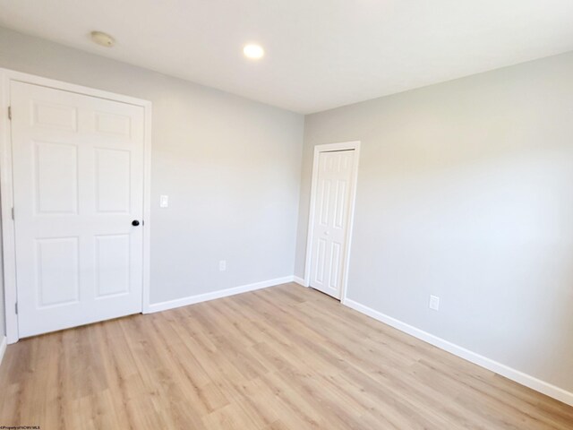 unfurnished bedroom with baseboards, recessed lighting, light wood finished floors, and a closet