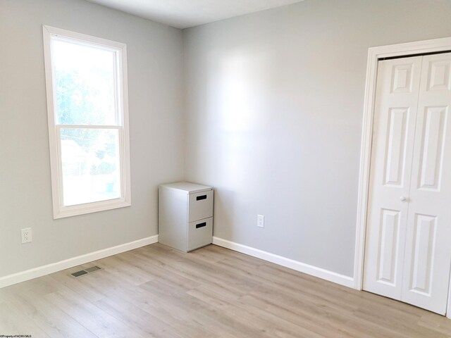 unfurnished bedroom with baseboards, multiple windows, light wood finished floors, and visible vents