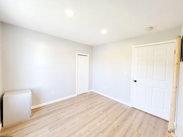 unfurnished bedroom featuring recessed lighting, baseboards, light wood finished floors, and a closet