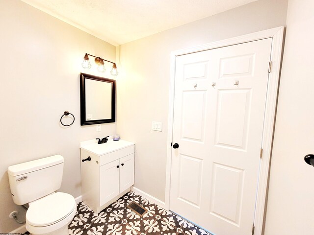 half bathroom featuring baseboards, toilet, and vanity