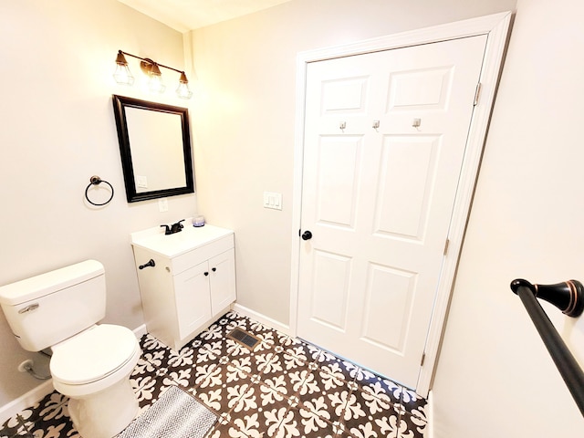 half bathroom featuring toilet, baseboards, and vanity