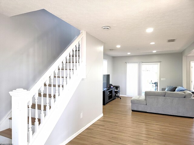 living room featuring recessed lighting, baseboards, wood finished floors, visible vents, and stairway