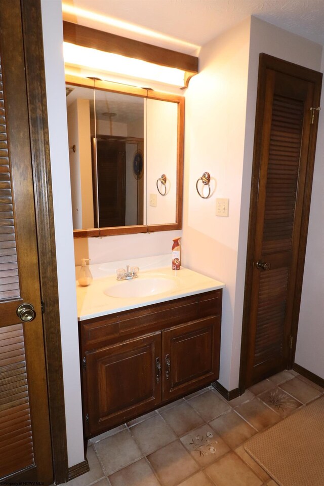 bathroom with baseboards, tile patterned flooring, and vanity