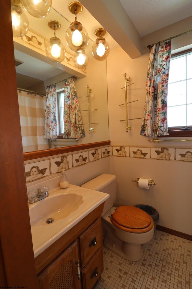 bathroom featuring wainscoting, toilet, plenty of natural light, and vanity