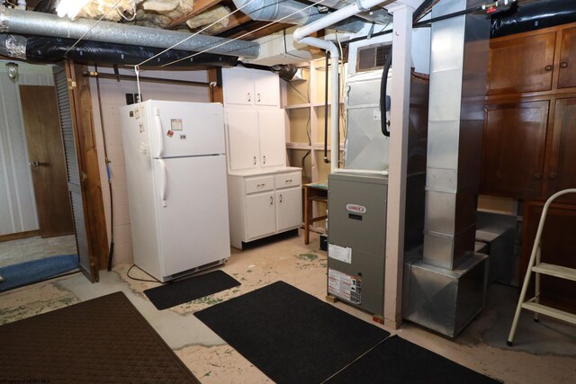 unfinished below grade area with freestanding refrigerator, visible vents, and heating unit