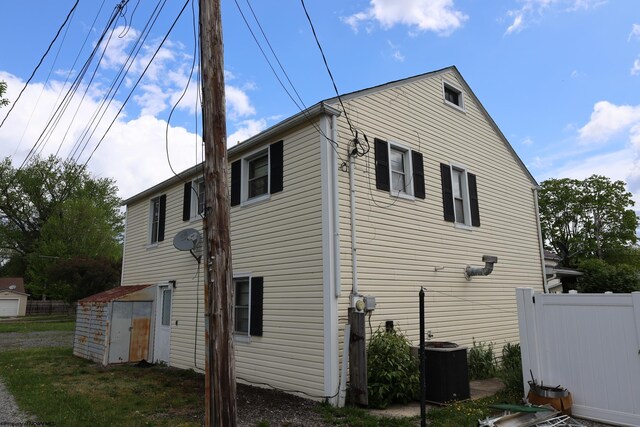 view of home's exterior with an outdoor structure, fence, a storage shed, and cooling unit