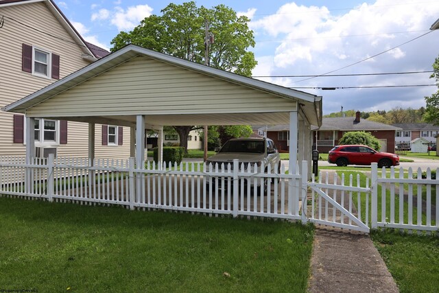 view of front of house with a fenced front yard, a detached carport, and a front lawn
