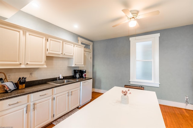 kitchen with ceiling fan, dark countertops, a sink, dishwasher, and backsplash