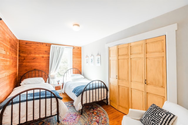 bedroom featuring wooden walls, a closet, and light wood-style floors