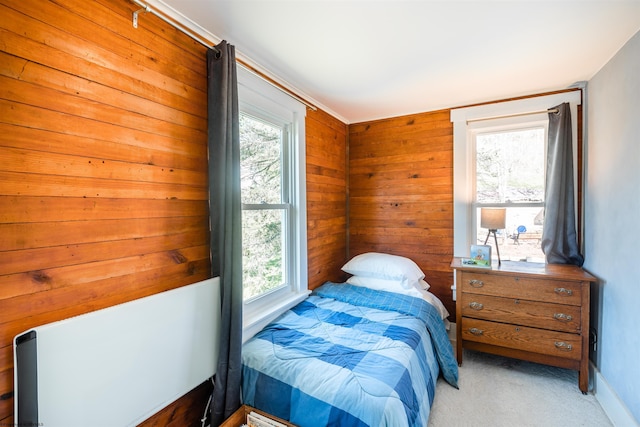 bedroom featuring baseboards, light carpet, and wood walls