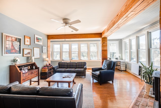 living area featuring light wood-type flooring, a ceiling fan, and baseboards