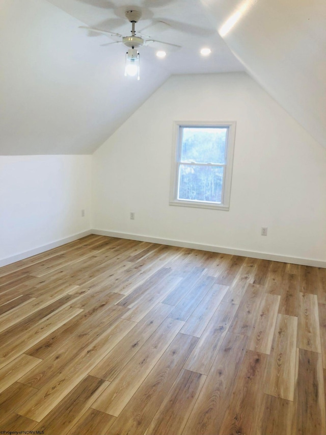 bonus room featuring light wood-style floors, baseboards, ceiling fan, and lofted ceiling