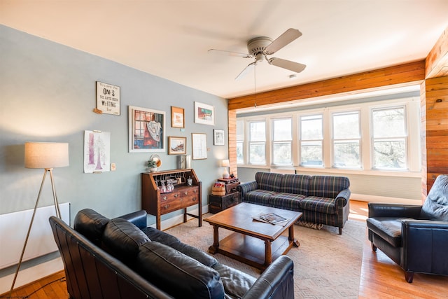 living area with wooden walls, a ceiling fan, and light wood-style flooring