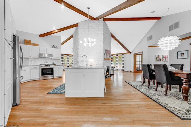 kitchen featuring appliances with stainless steel finishes, under cabinet range hood, high vaulted ceiling, and visible vents