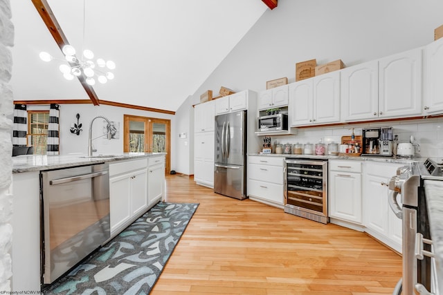 kitchen featuring decorative backsplash, beverage cooler, light wood-style floors, a sink, and appliances with stainless steel finishes