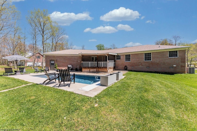 back of property with a patio, central air condition unit, a yard, and brick siding