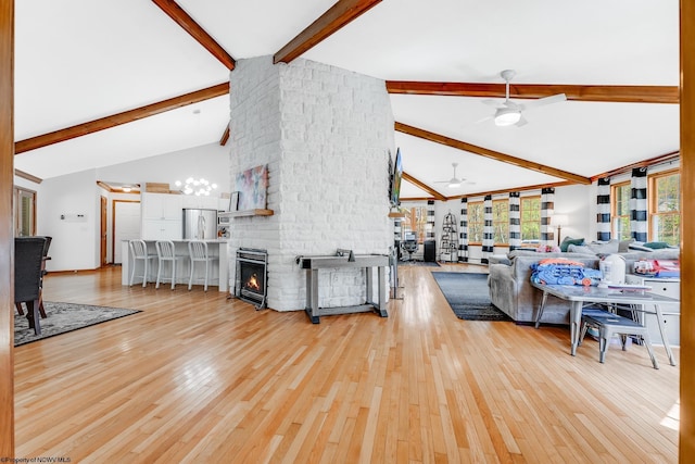 living area with ceiling fan, a large fireplace, wood finished floors, high vaulted ceiling, and beamed ceiling