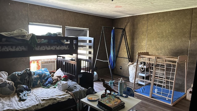 bedroom featuring a textured ceiling, cooling unit, and wood finished floors