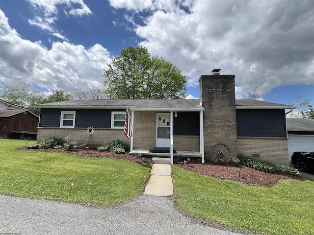 ranch-style home featuring brick siding, a front yard, a chimney, and a porch