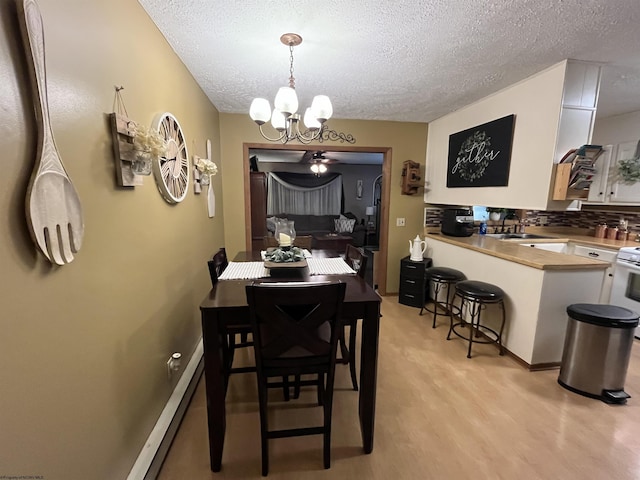 dining room with a baseboard heating unit, a textured ceiling, a chandelier, and light wood finished floors