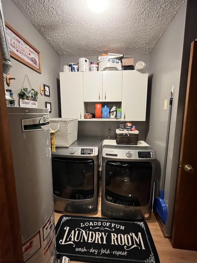 laundry room featuring light wood-type flooring, a textured ceiling, cabinet space, and independent washer and dryer