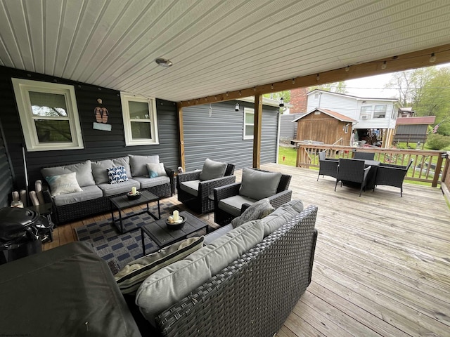 wooden deck featuring outdoor dining area, a storage unit, an outbuilding, and an outdoor hangout area