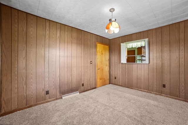 unfurnished room with carpet flooring, baseboard heating, and wood walls
