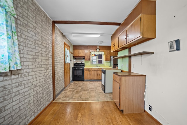 kitchen featuring light wood-style floors, range, brown cabinets, and brick wall