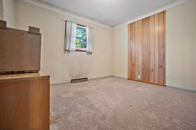 carpeted spare room with baseboards, ornamental molding, and a baseboard heating unit