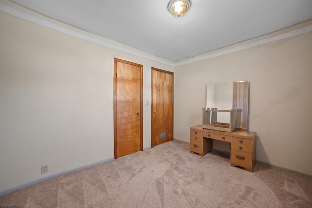 unfurnished bedroom with carpet flooring, ornamental molding, and two closets