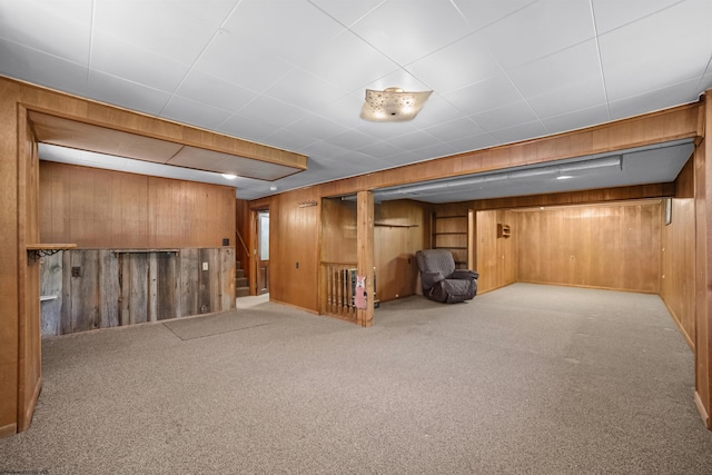 finished below grade area with carpet flooring, wood walls, and stairs