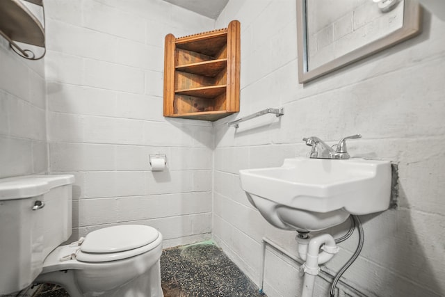 half bath featuring concrete block wall and toilet