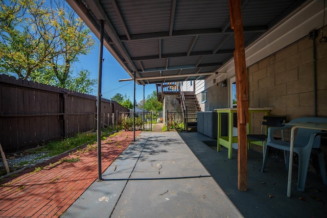 view of patio featuring fence, stairway, and a carport
