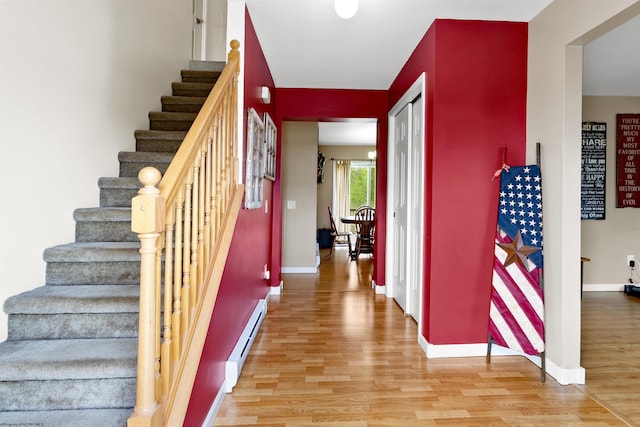 stairs with baseboards, a baseboard heating unit, and wood finished floors