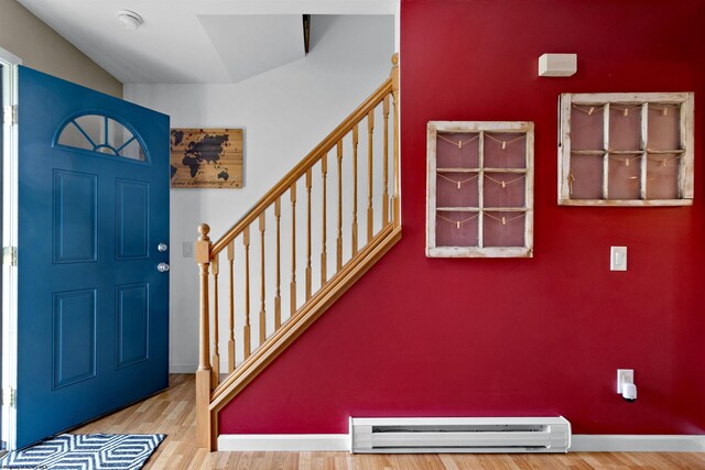 entrance foyer with stairway, baseboards, baseboard heating, and wood finished floors