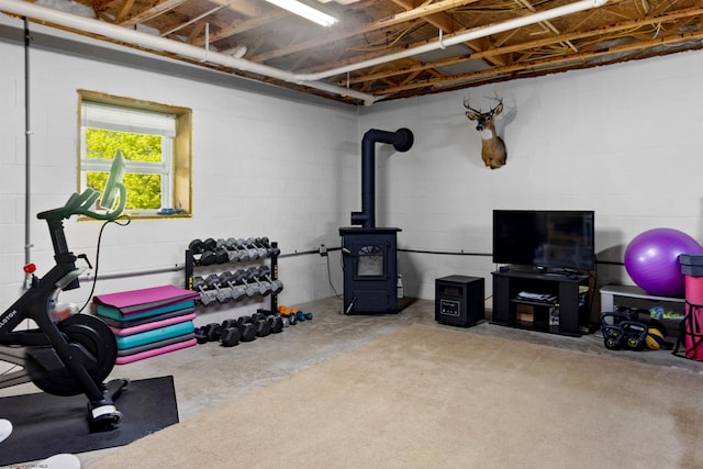 workout room featuring a wood stove and concrete block wall
