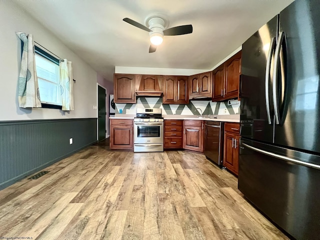 kitchen featuring freestanding refrigerator, stainless steel gas range oven, light countertops, light wood finished floors, and dishwasher