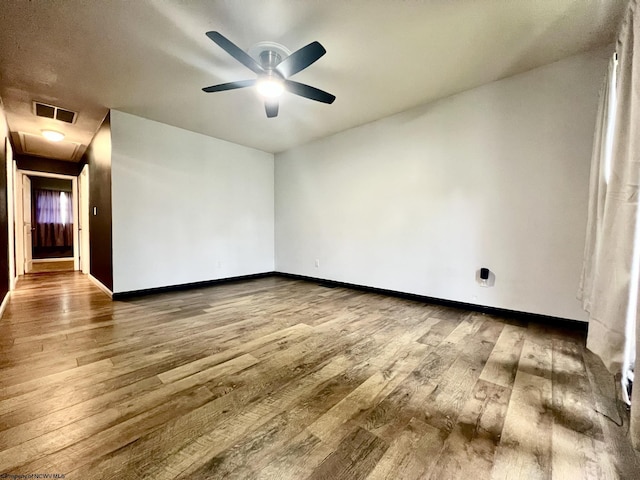 spare room with baseboards, ceiling fan, wood-type flooring, and visible vents