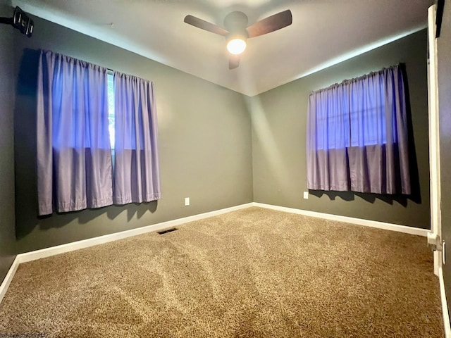 spare room with carpet floors, baseboards, a ceiling fan, and visible vents
