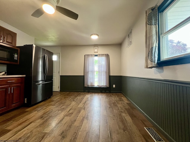 kitchen with a ceiling fan, visible vents, black microwave, freestanding refrigerator, and dark wood-style floors