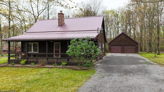 view of front of property featuring covered porch, a garage, a chimney, metal roof, and an outbuilding