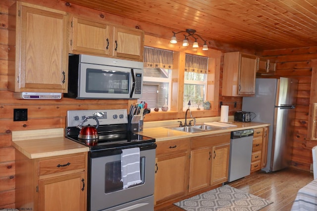 kitchen with a sink, light wood-style flooring, light countertops, and appliances with stainless steel finishes